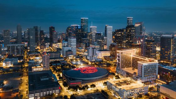 Aerial view of a city skyline at dusk with lit skyscrapers and a brightly lit stadium