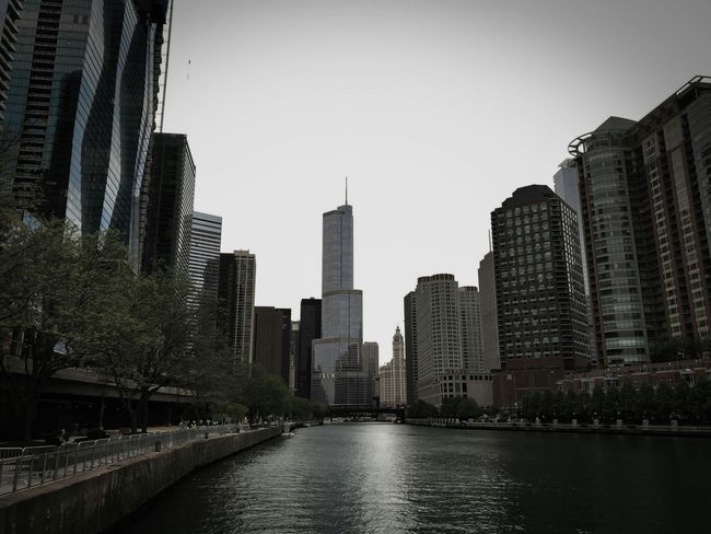 City skyline with tall buildings along a river under a cloudy sky