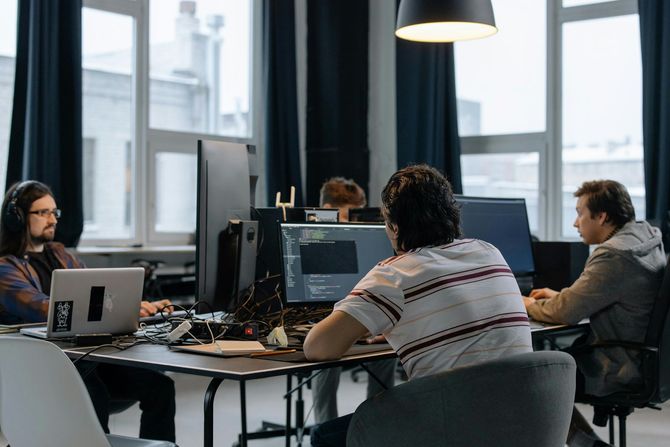 Team meeting in a modern office with people working on laptops around a table