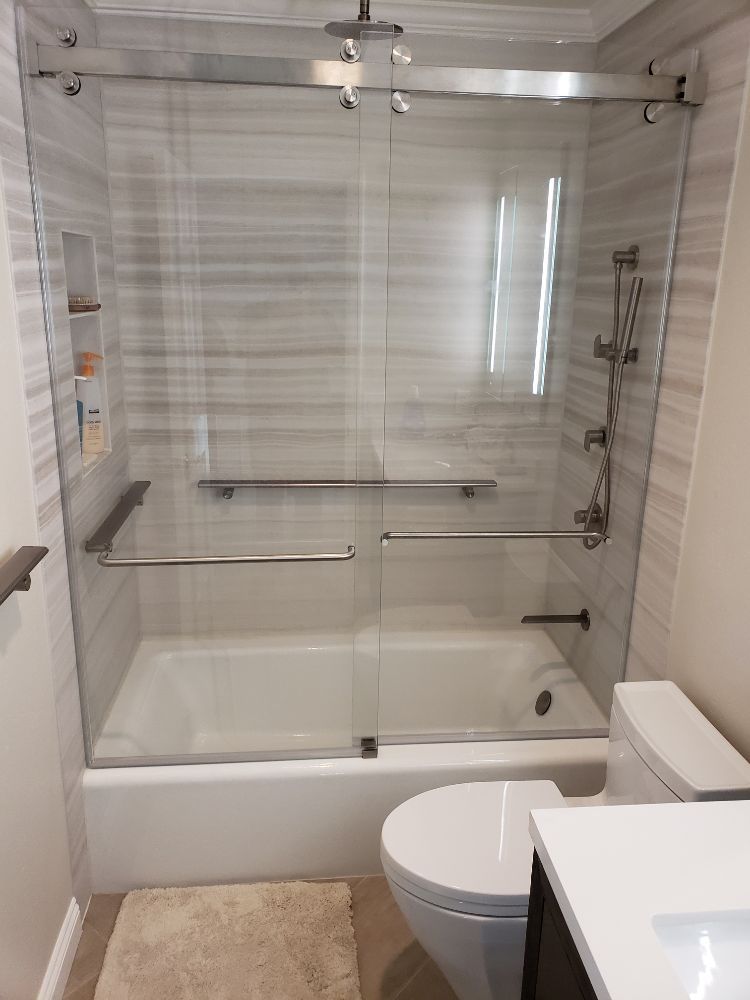 A bathroom with a sliding glass shower door , tub , toilet and sink.