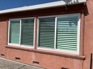 A house with three windows and shutters on it.