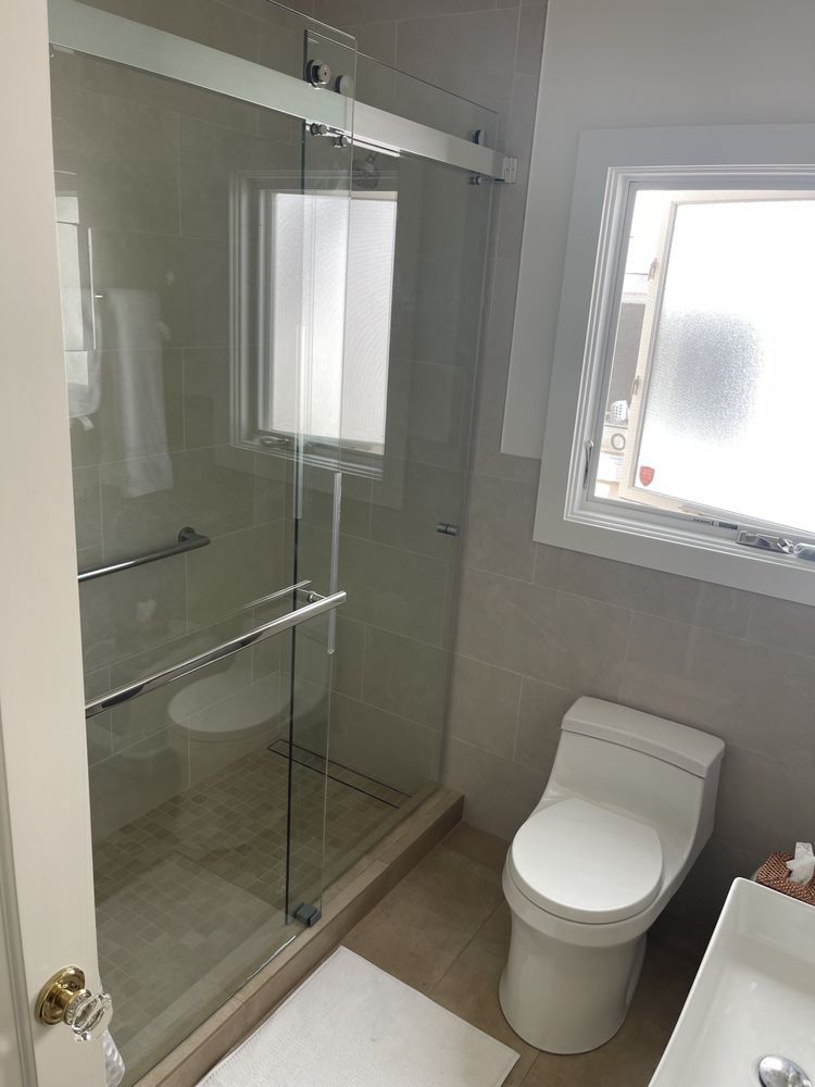 A bathroom with a toilet , sink and shower stall.
