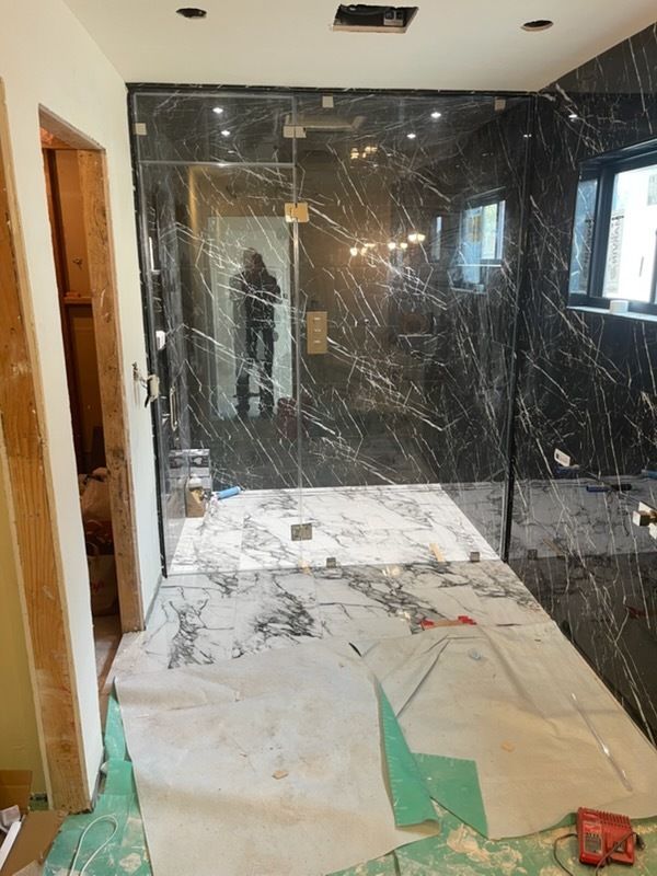 Damaged room with black marble wall panels, broken glass, and construction debris on the floor.