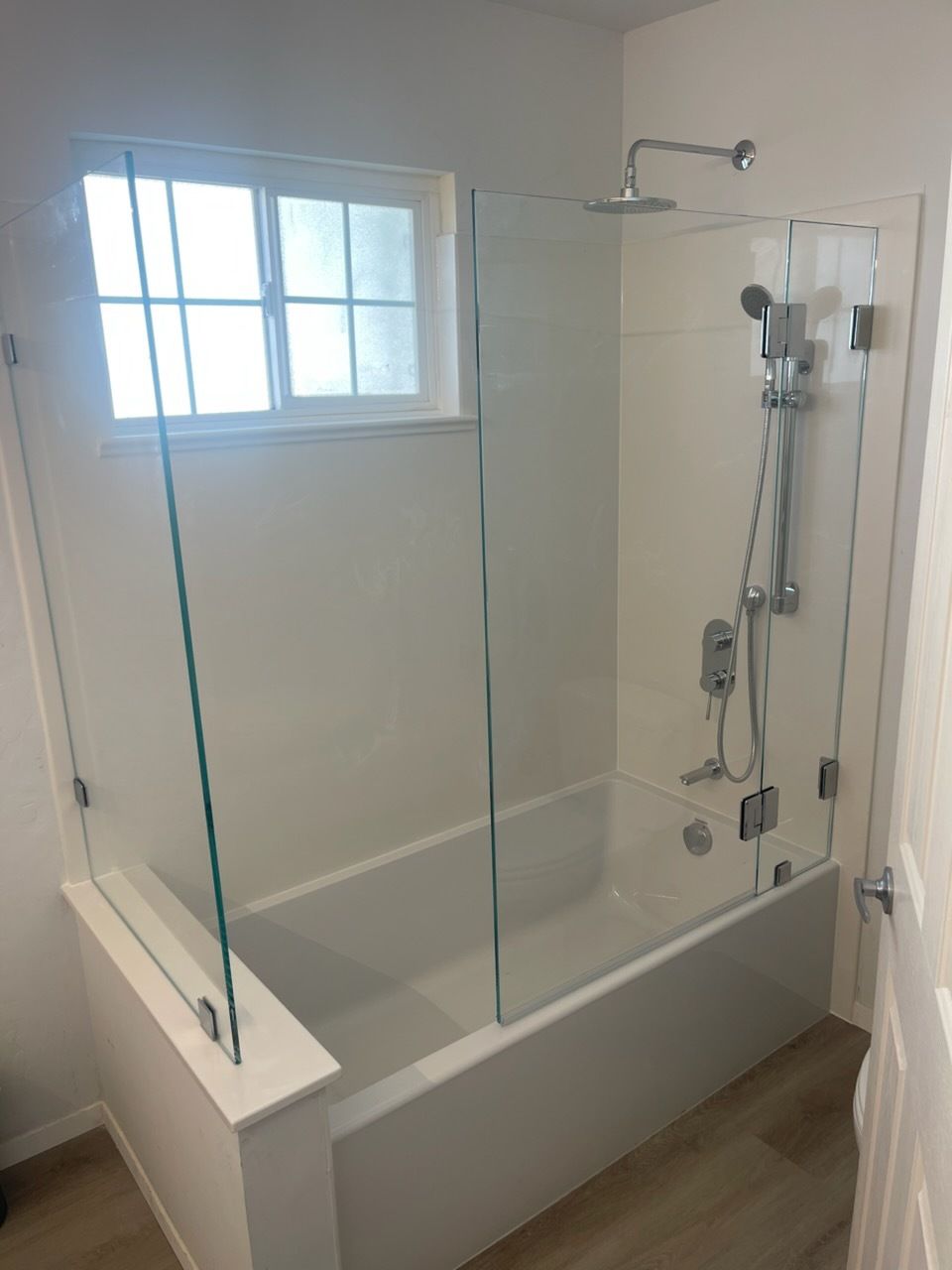 Walk-in bathtub with glass shower enclosure, chrome showerhead, and window above the tub