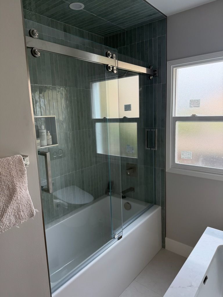 Modern bathroom with glass-enclosed shower, white tub, and tiled walls
