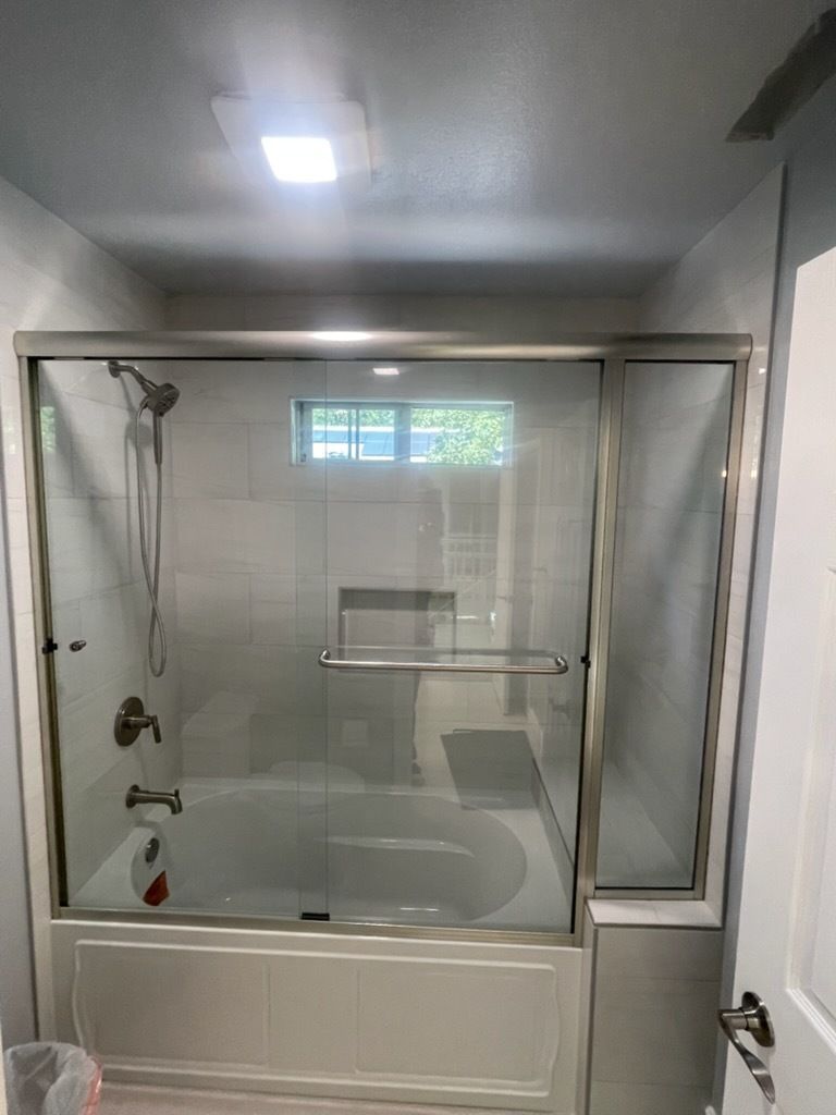 Bathroom with a shower-tub combo, glass enclosure, and a small window above the tub.