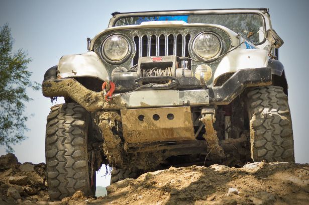 A jeep is driving down a muddy hill.