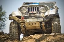 A jeep is driving down a muddy hill.