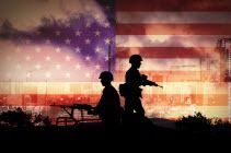 Two soldiers are standing in front of an american flag.