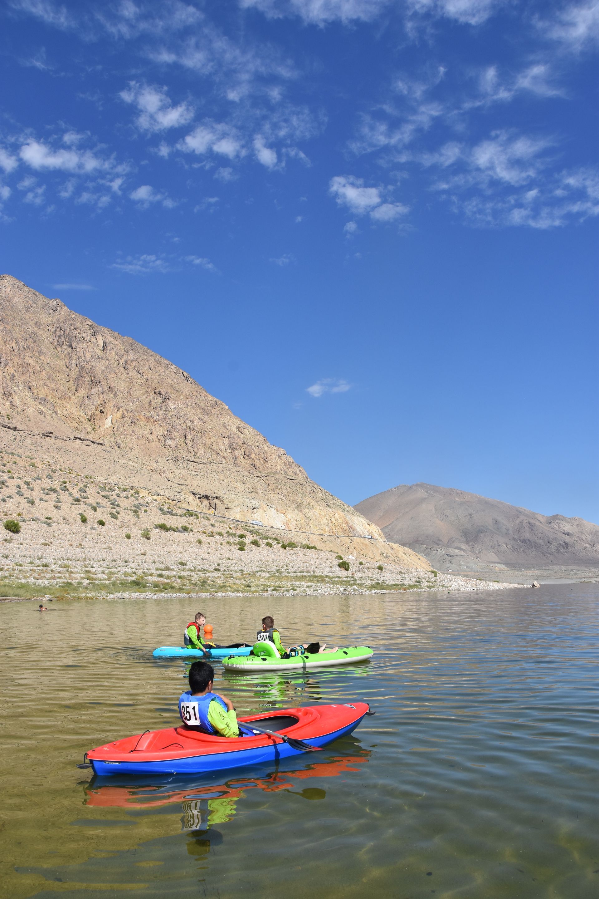 A group of people are kayaking on a lake with mountains in the background.