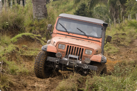 A jeep is driving through a muddy field.