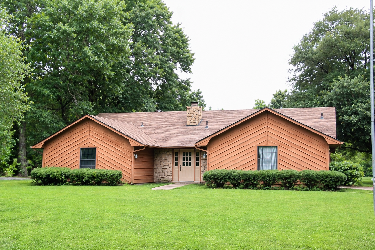 Single-story brick house with a shingled roof, front lawn, and trees in the yard