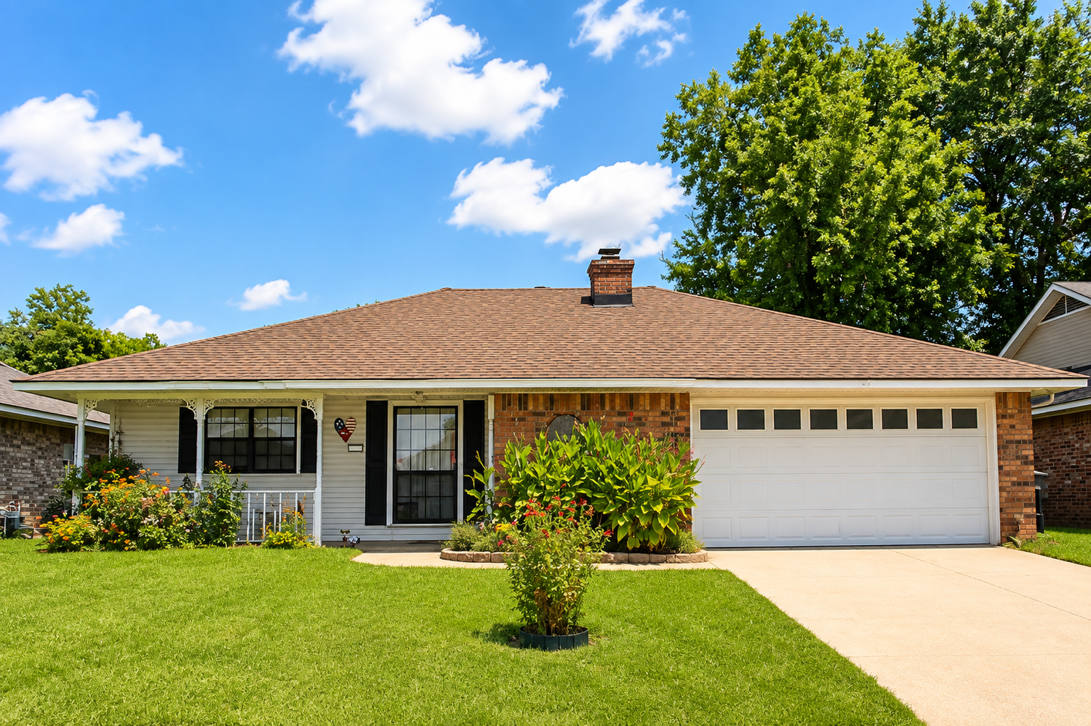 Single-story beige house with a front porch, garage, and a green lawn under a blue sky.