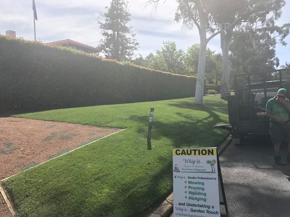 A sign that says caution is in front of a lush green field.