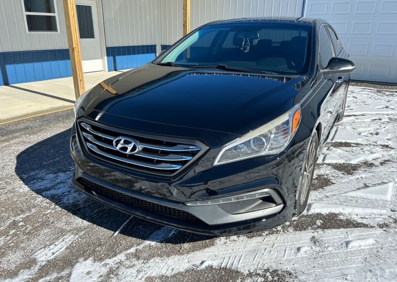 a black mazda 6 is parked in a gravel lot next to a truck .
