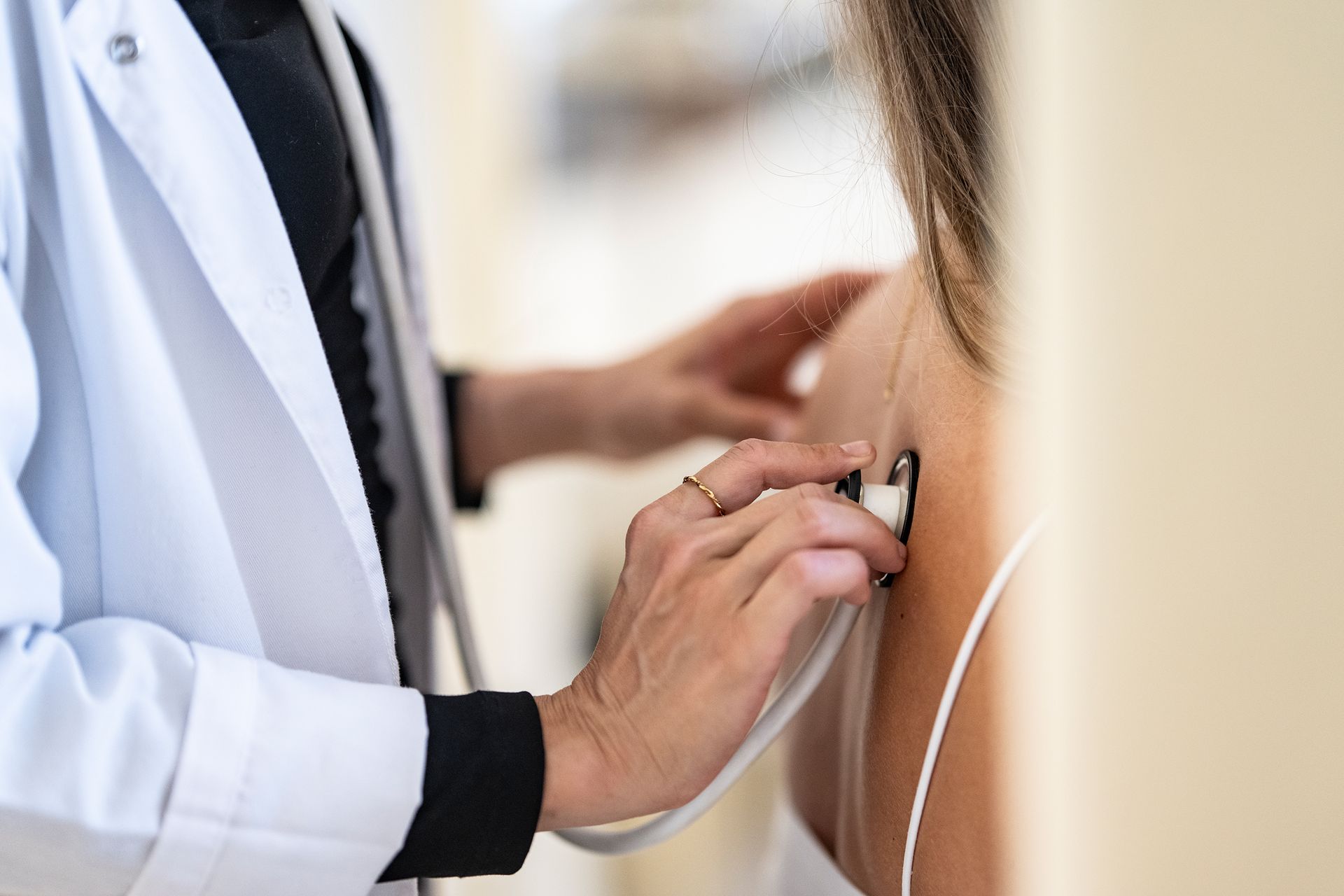 Arzt untersucht in einer Klinik mit einem Stethoskop den Rücken eines Patienten