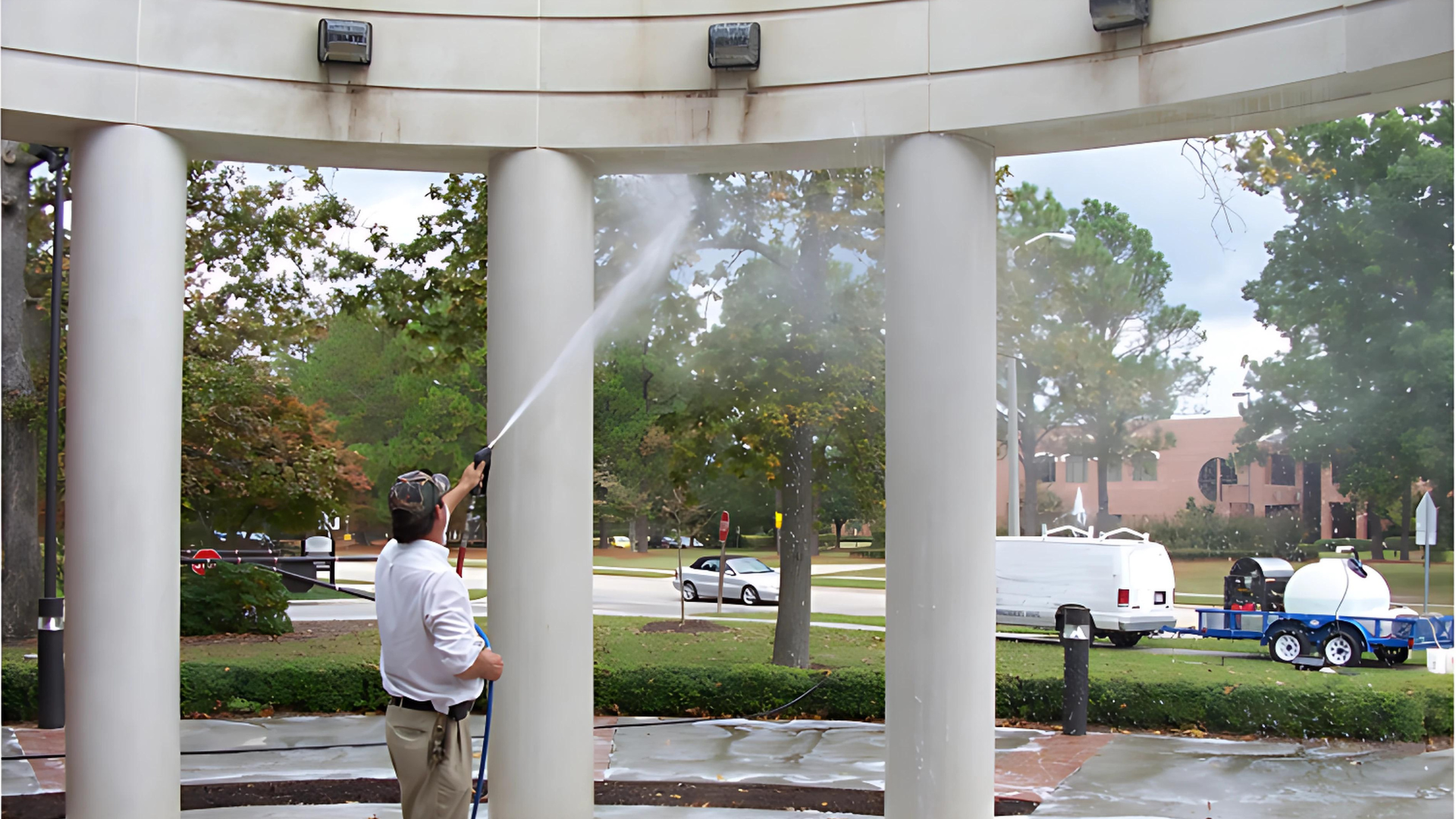 A man is using a high pressure washer to clean a pillar