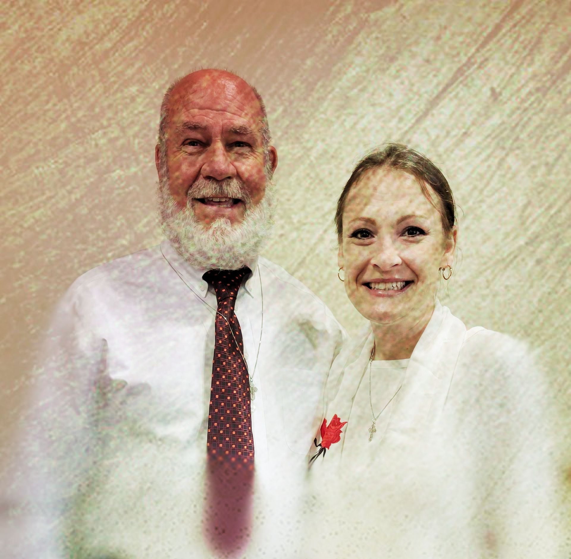 A man with a beard is standing next to a woman in a white shirt and tie.