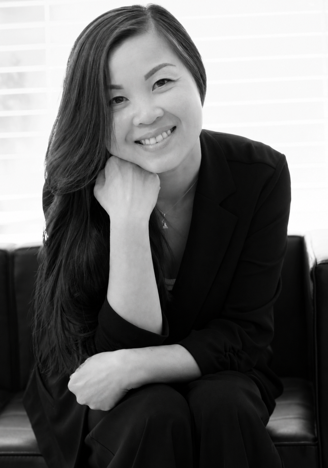 A woman in a suit is smiling in a black and white photo.