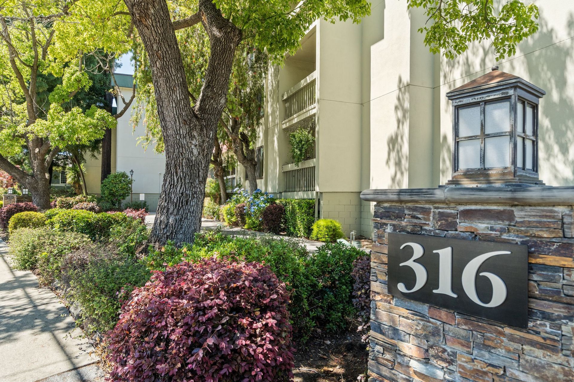 A condo with a stone wall and a sign that says 316 on it.