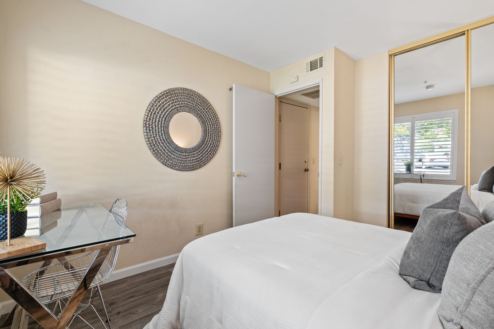 A bedroom with a bed , desk , chairs and a mirror.