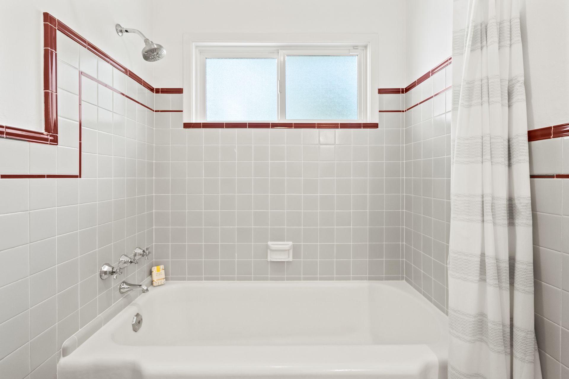 A bathroom with a bathtub , shower , and window.