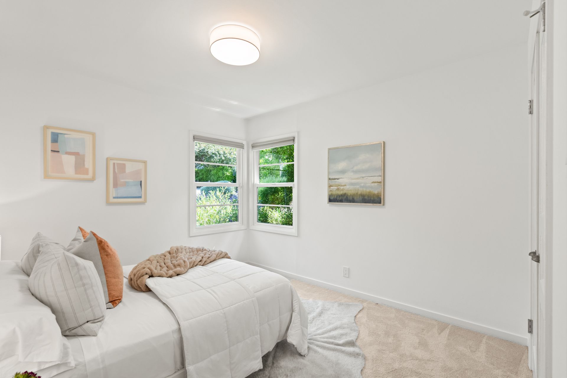 A bedroom with a bed , two windows and a rug.