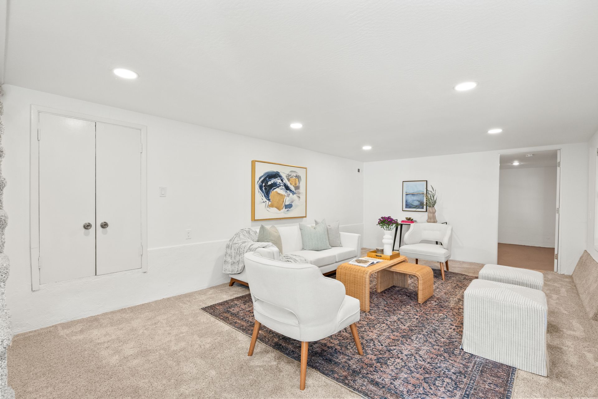 A living room with white furniture and a rug.