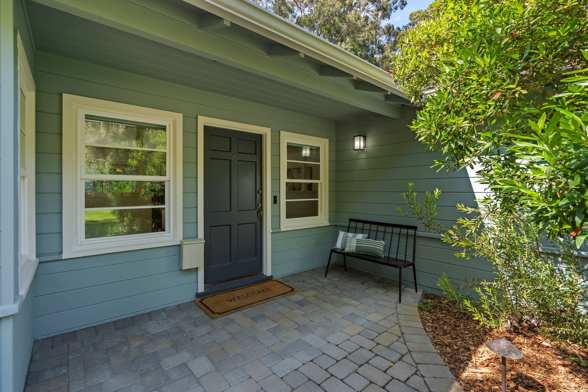 A house with a black door and a bench in front of it.