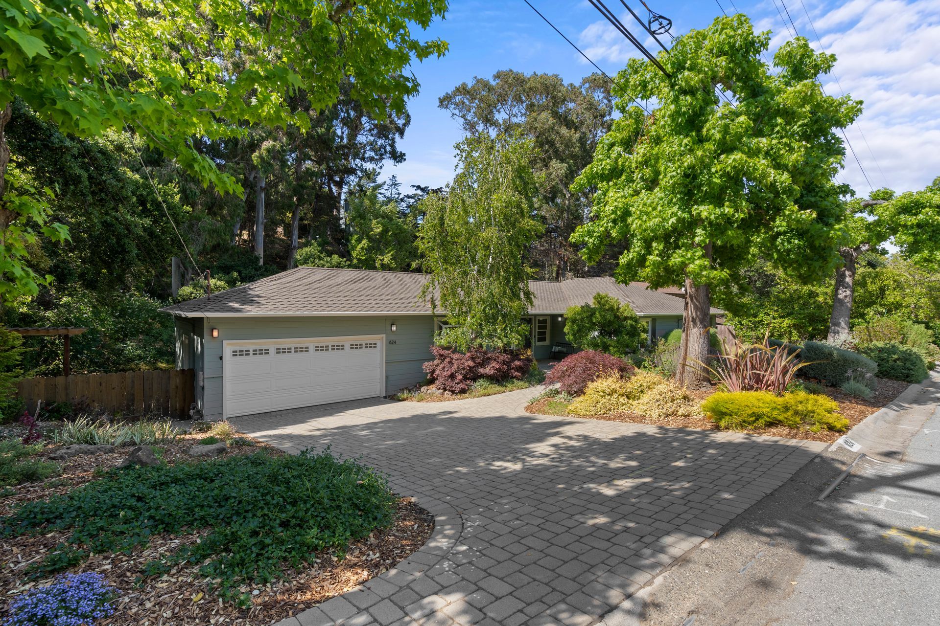 A house with a garage and a driveway surrounded by trees.