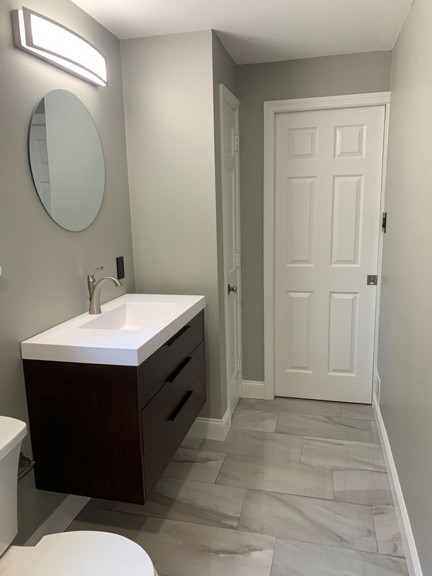 Bright white bathroom with freestanding tub, glass shower, marble finishes, and navy vanity with gold fixtures Bright white bathroom with freestanding tub, glass shower, marble finishes, and navy vanity with gold fixtures