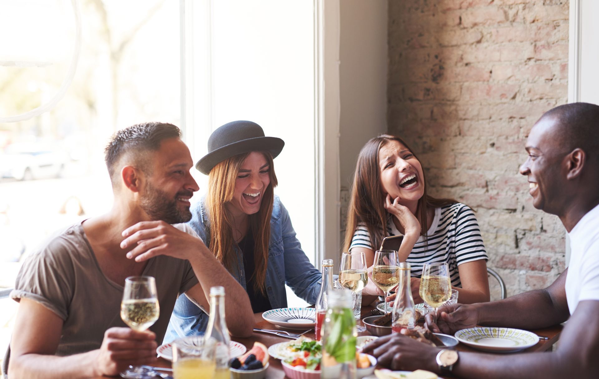 A group of people are sitting at a table eating food and drinking wine.