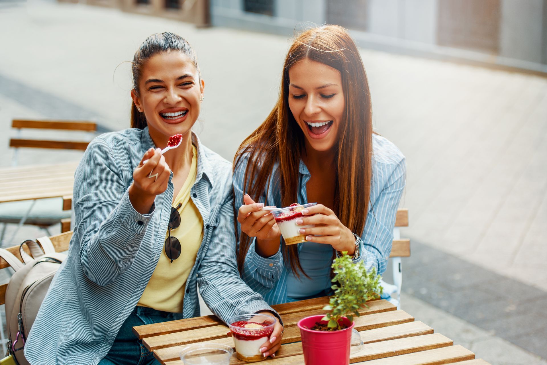 Two women are sitting at a table eating ice cream.