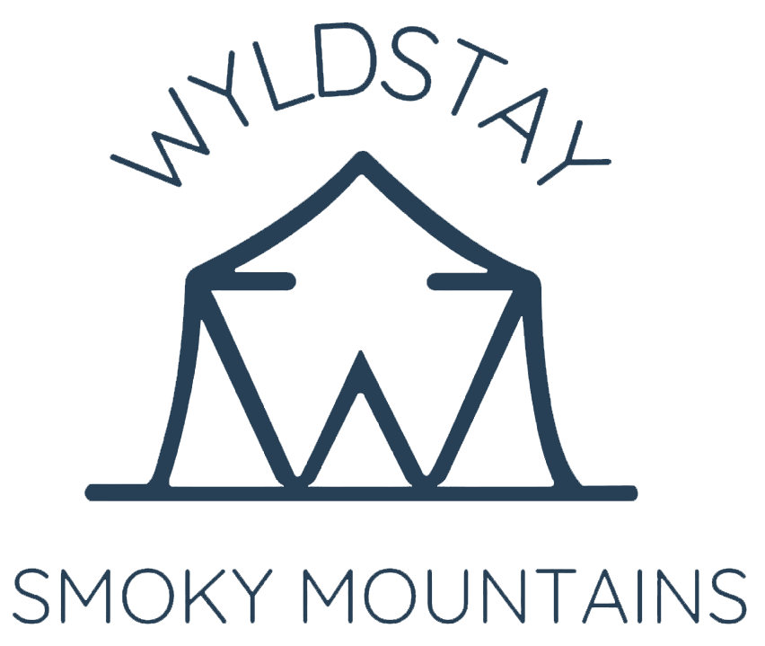 The logo for wildstay smoky mountains is a tent with a mountain in the background.