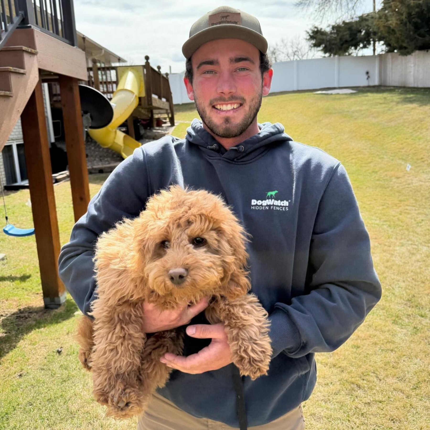 Earl Outdoor Solutions DogWatch installer with Goldendoodle puppy in Omaha yard