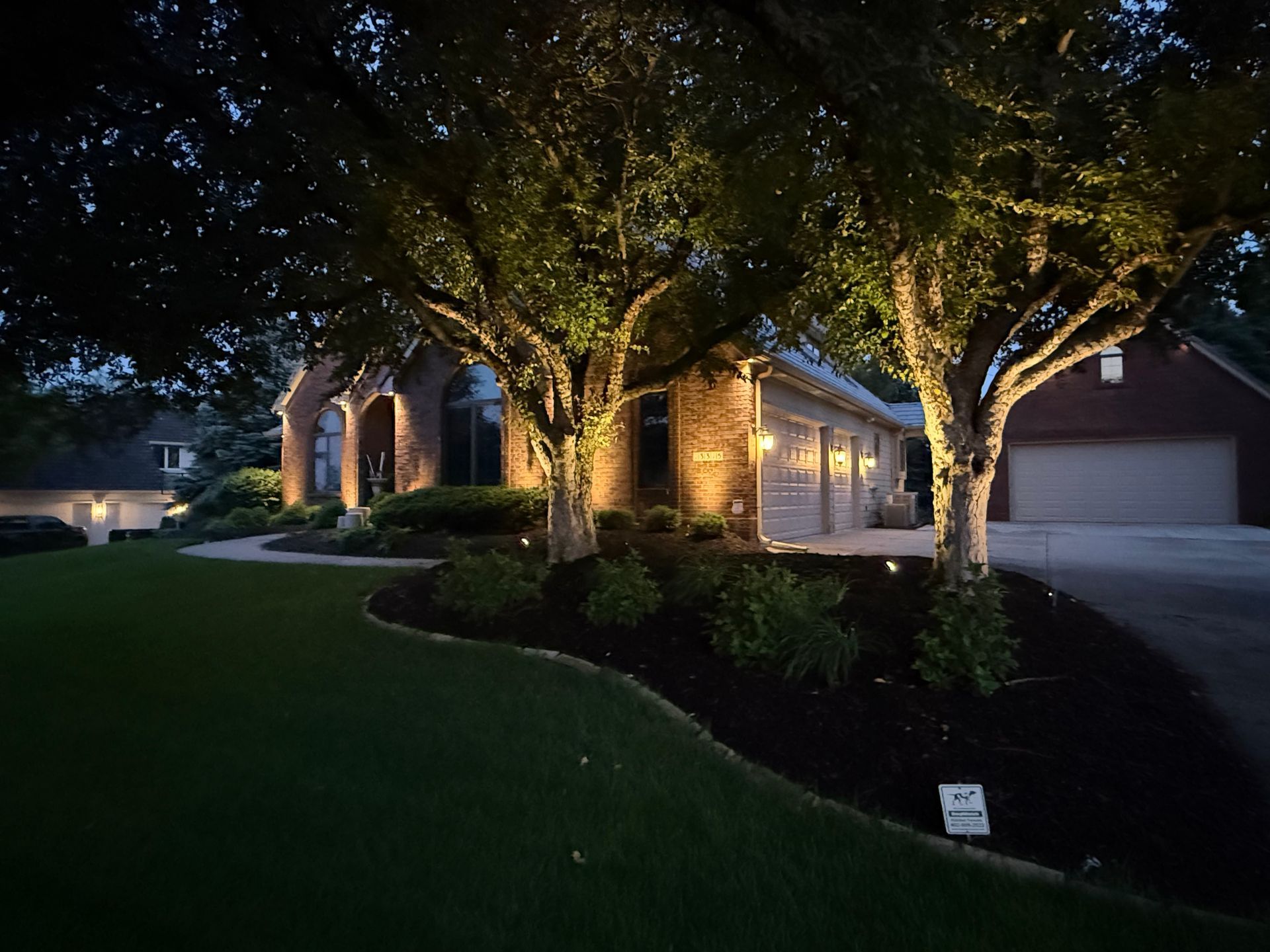 Alliance outdoor lighting spotlights on trees and home facade — Earl Outdoor Solutions Omaha