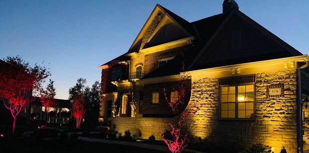 Premium Alliance landscape lighting on luxury stone home at dusk — Omaha Nebraska
