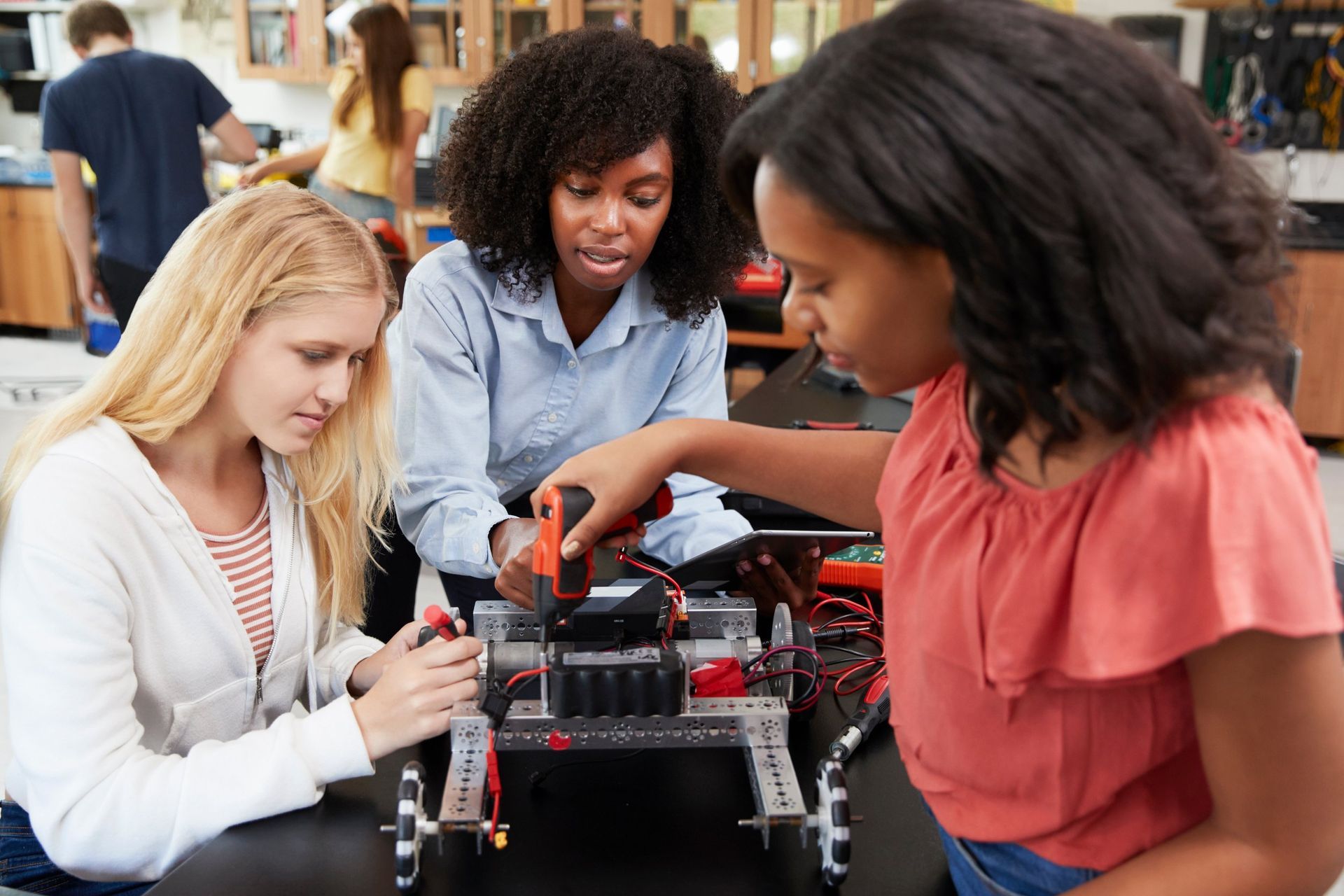 A group of young women are working on a robot in a lab.