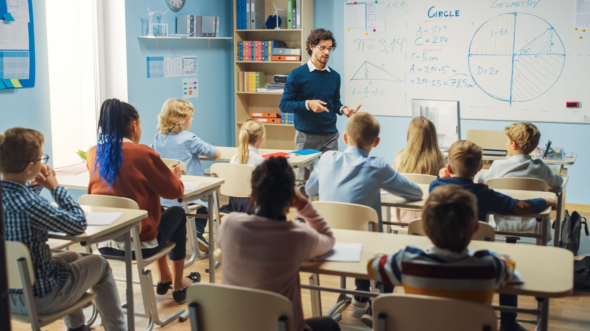 A woman is writing on a whiteboard in a classroom.