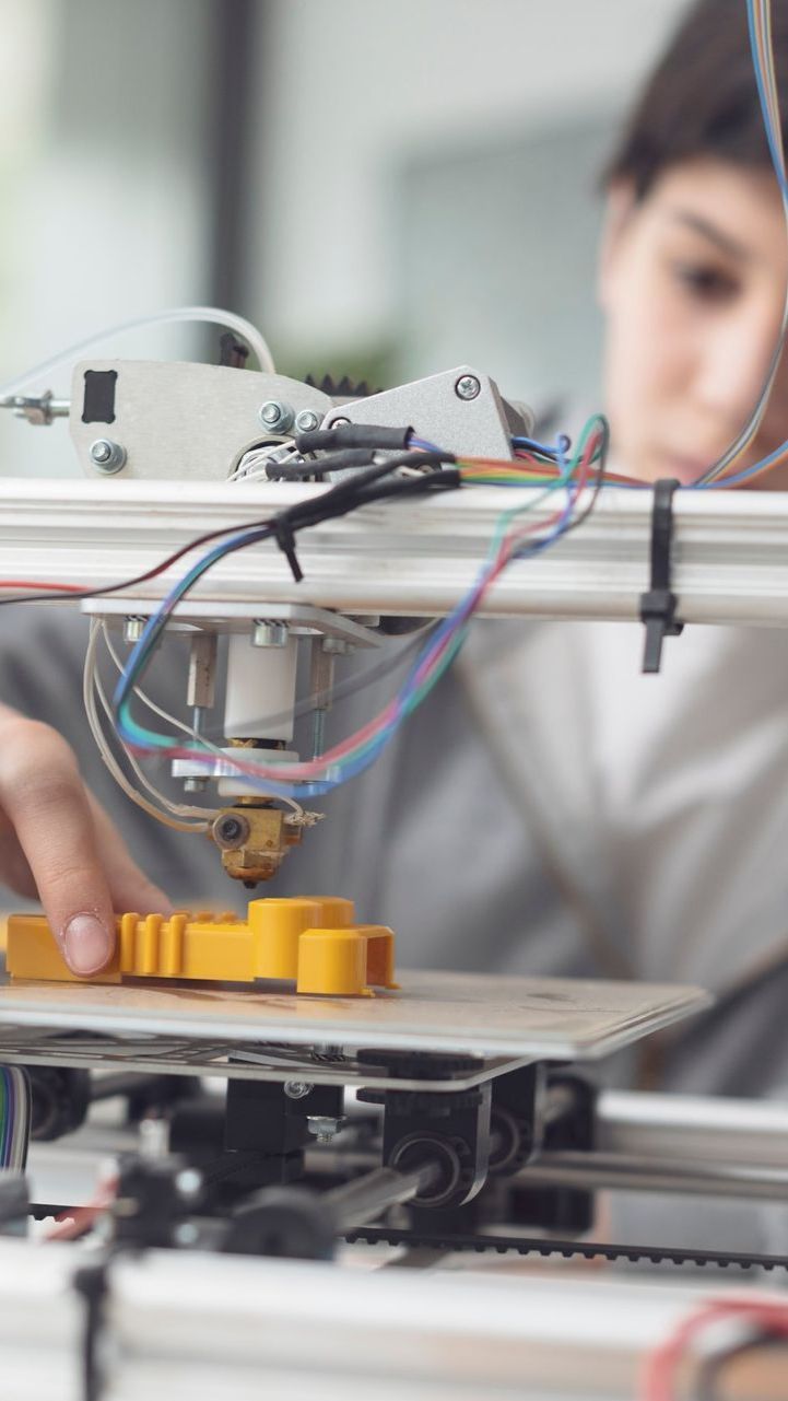 A person is using a 3d printer to print a yellow object.
