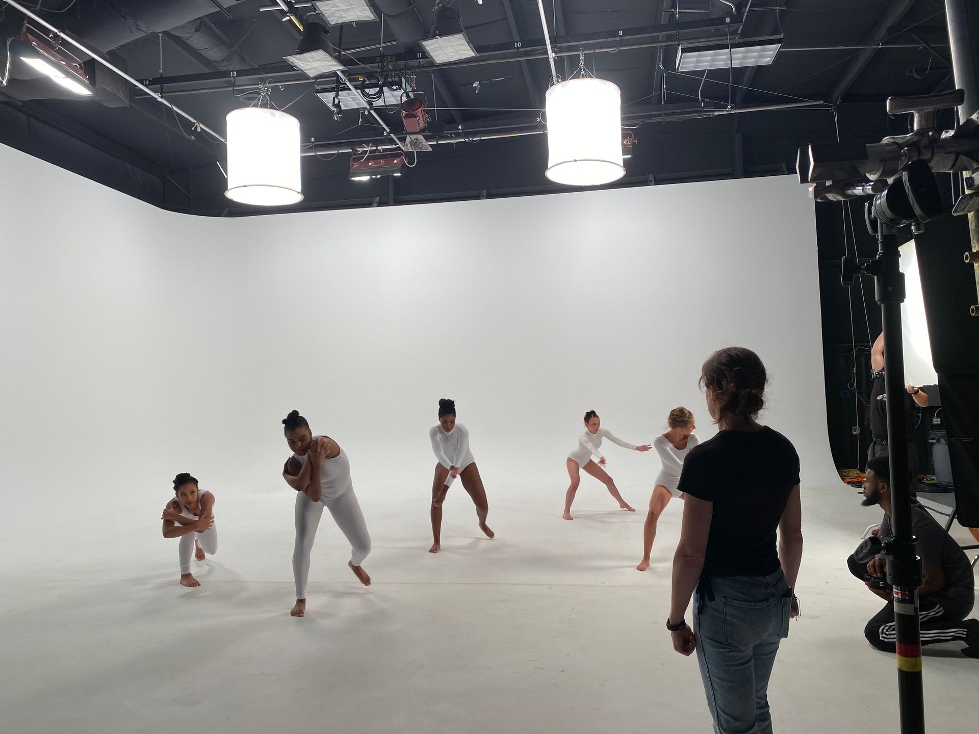 A group of people are dancing in a white room.