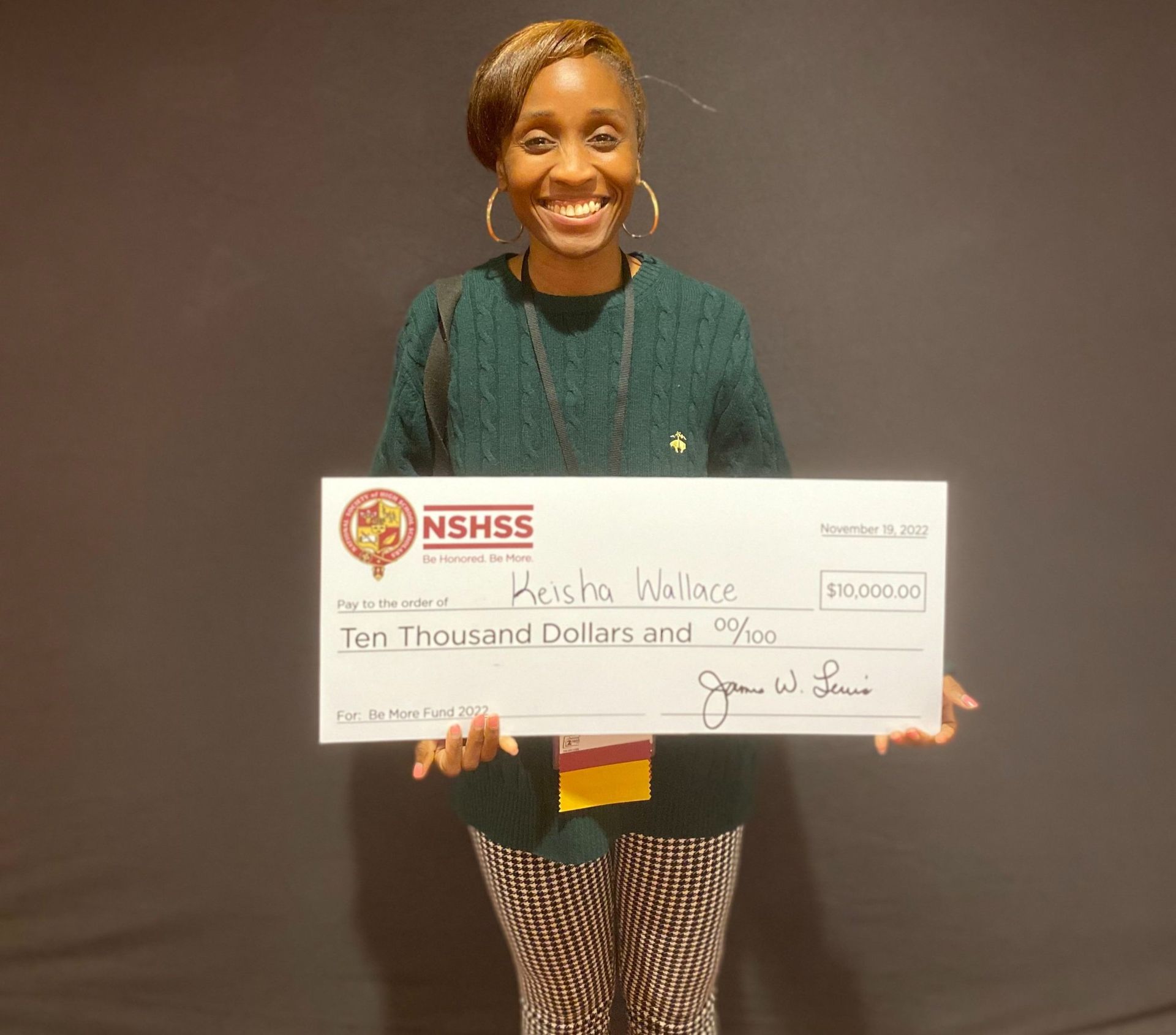 Keisha Wallace holding a large check in her hands.