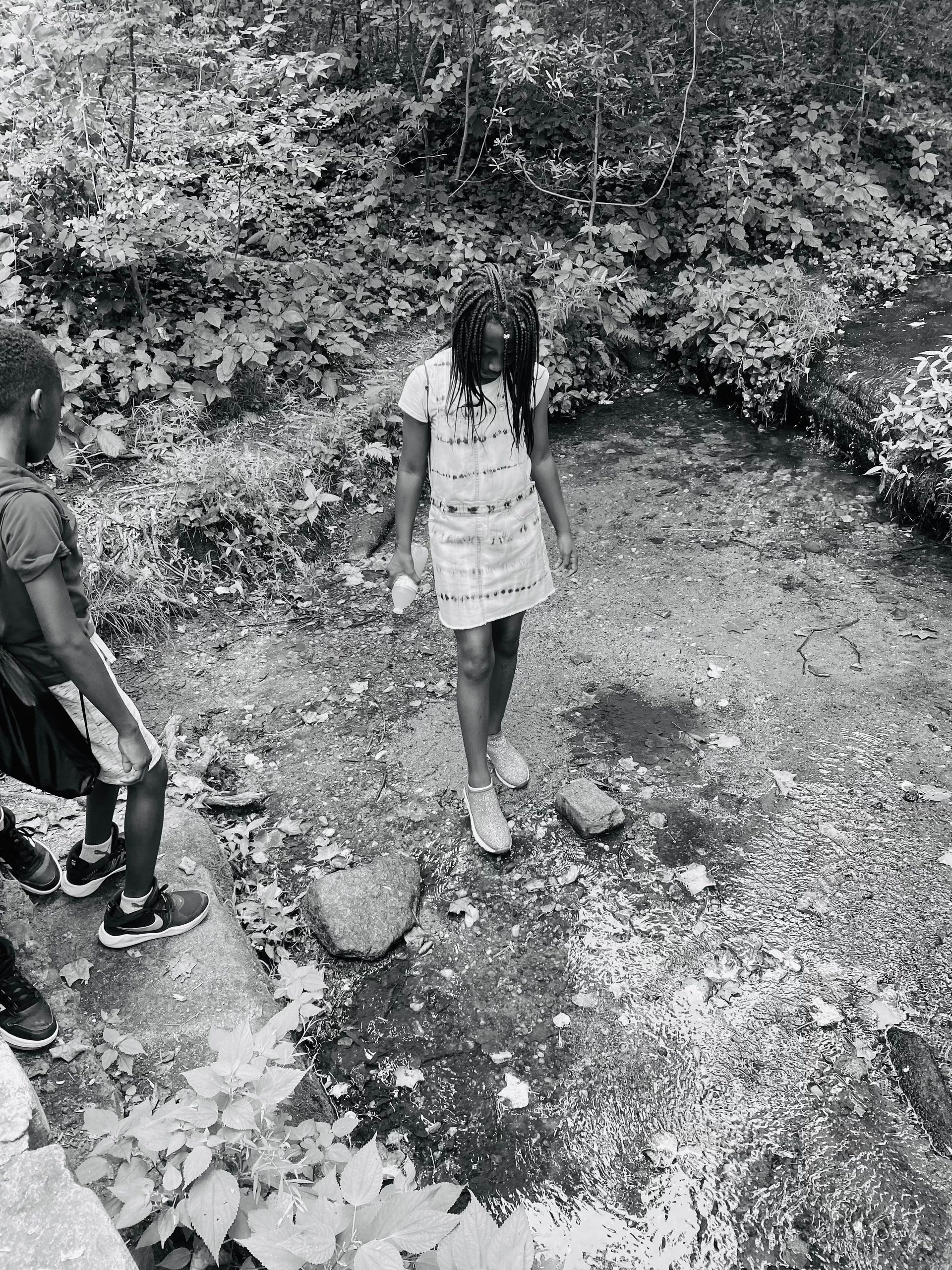 A black and white photo of two children playing in a stream.
