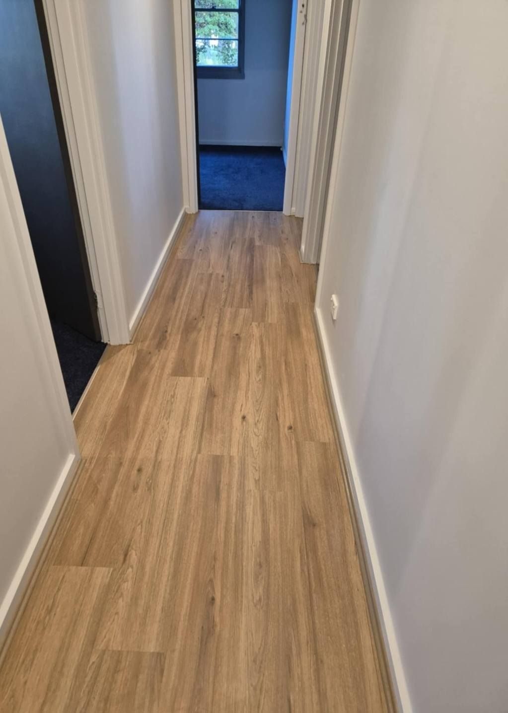 Hallway with Light Brown Wood-Look Flooring, White Trim, and Grey Walls — Canberra Floor Coverings in Queanbeyan West, NSW
