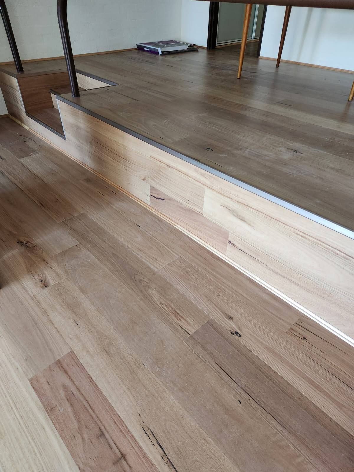 Wooden Floor with A Raised Platform, Metal Trim, and A Single Step Down — Canberra Floor Coverings in Queanbeyan West, NSW