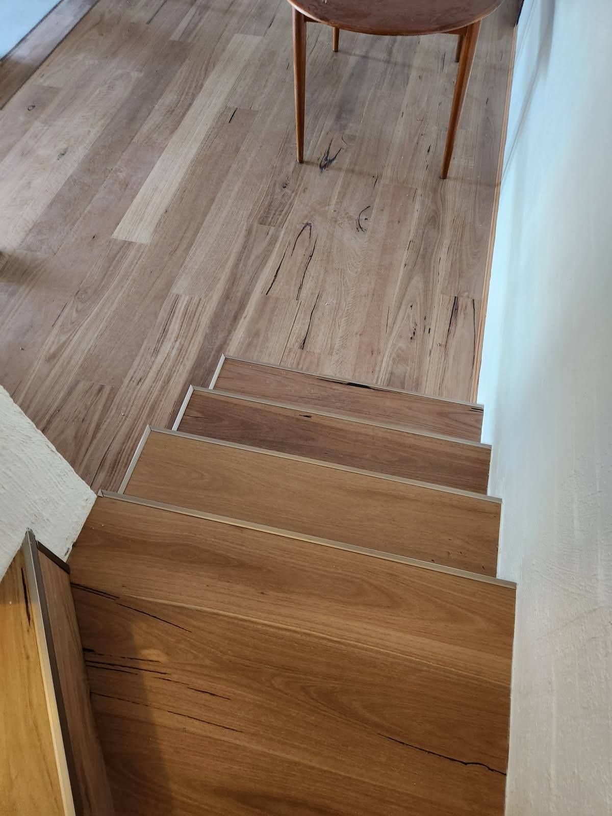 Wooden Stairs Leading Down from A Light Wood Floor; a Small Table Stands Above — Canberra Floor Coverings in Queanbeyan West, NSW
