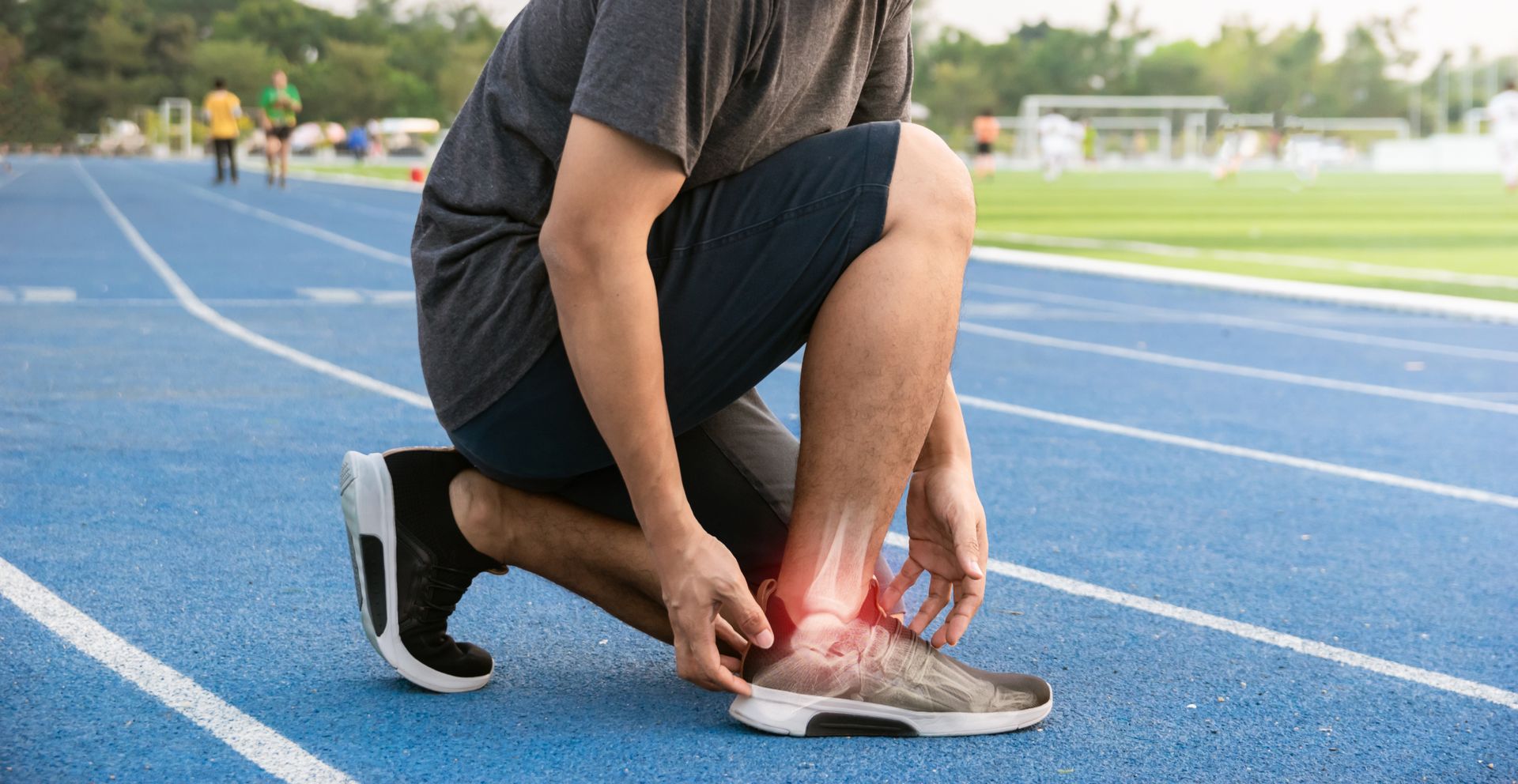 Person on track, kneeling, holding ankle, showing red inflammation, possible injury.
