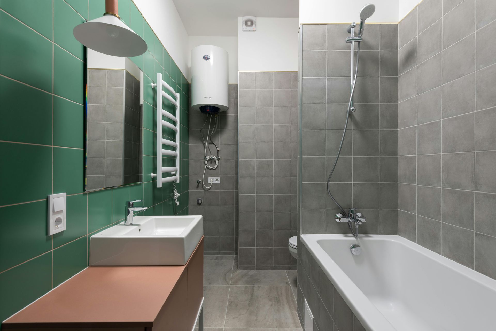 Modern bathroom with green tile walls, vanity sink, towel warmer, and bathtub with shower.