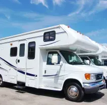 White RVs parked in a row under a blue sky