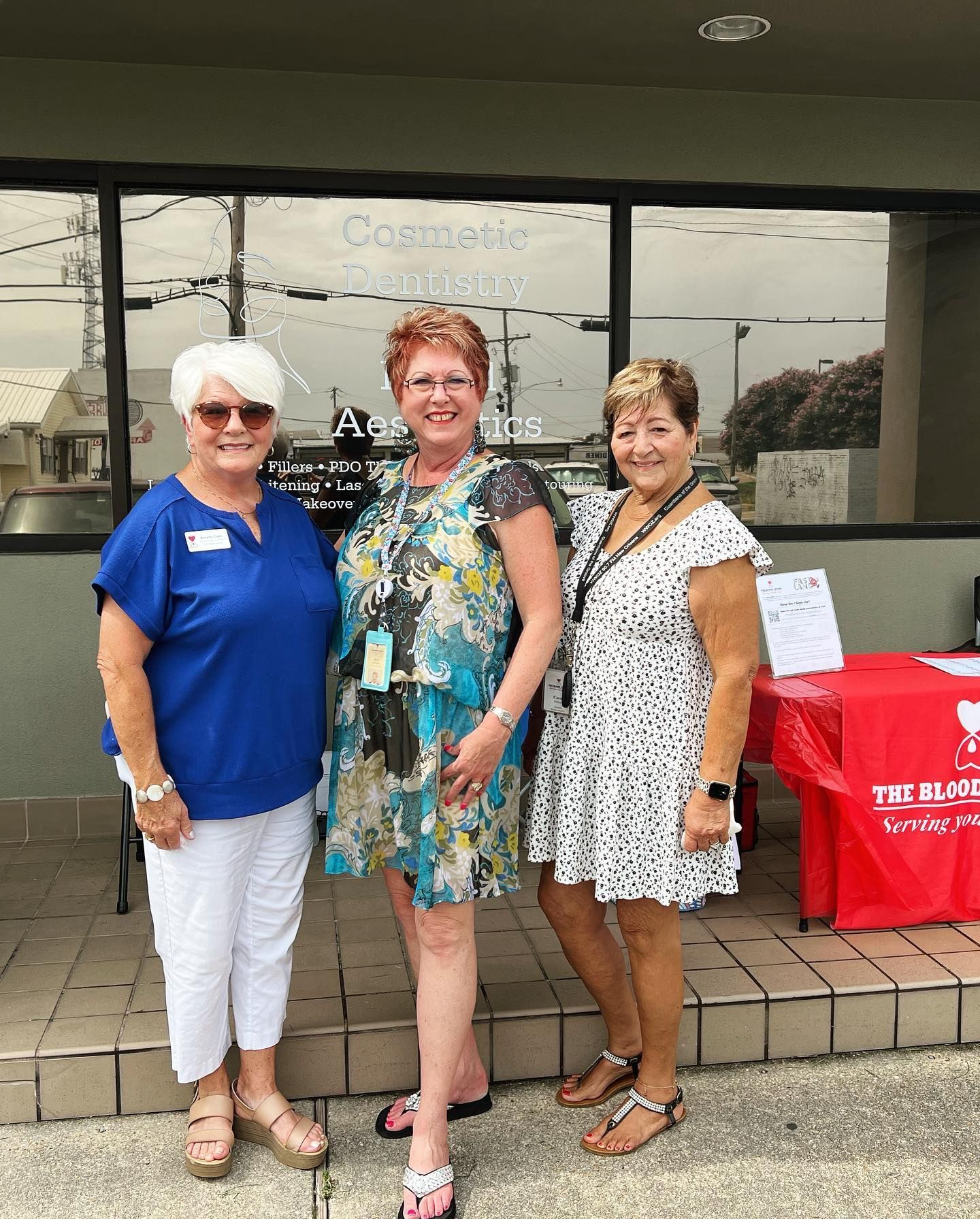 Three women stand in front of a dental office. 